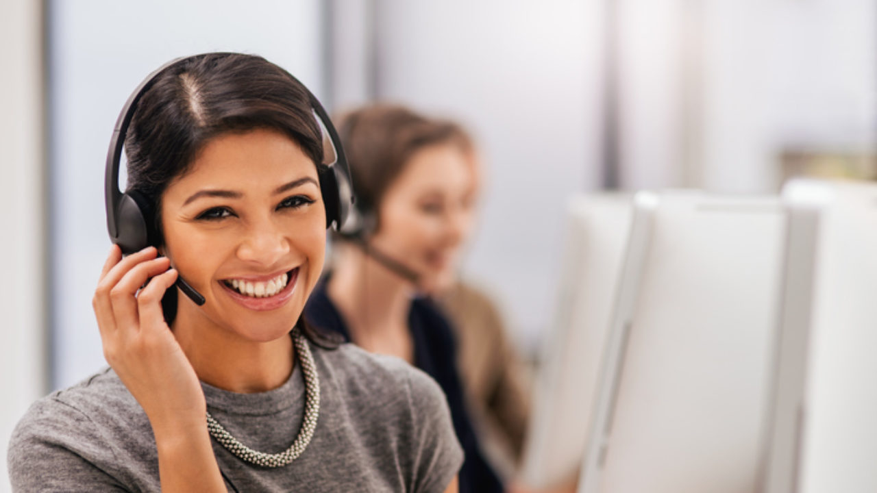 Smiling customer service representative wearing a headset assisting a client